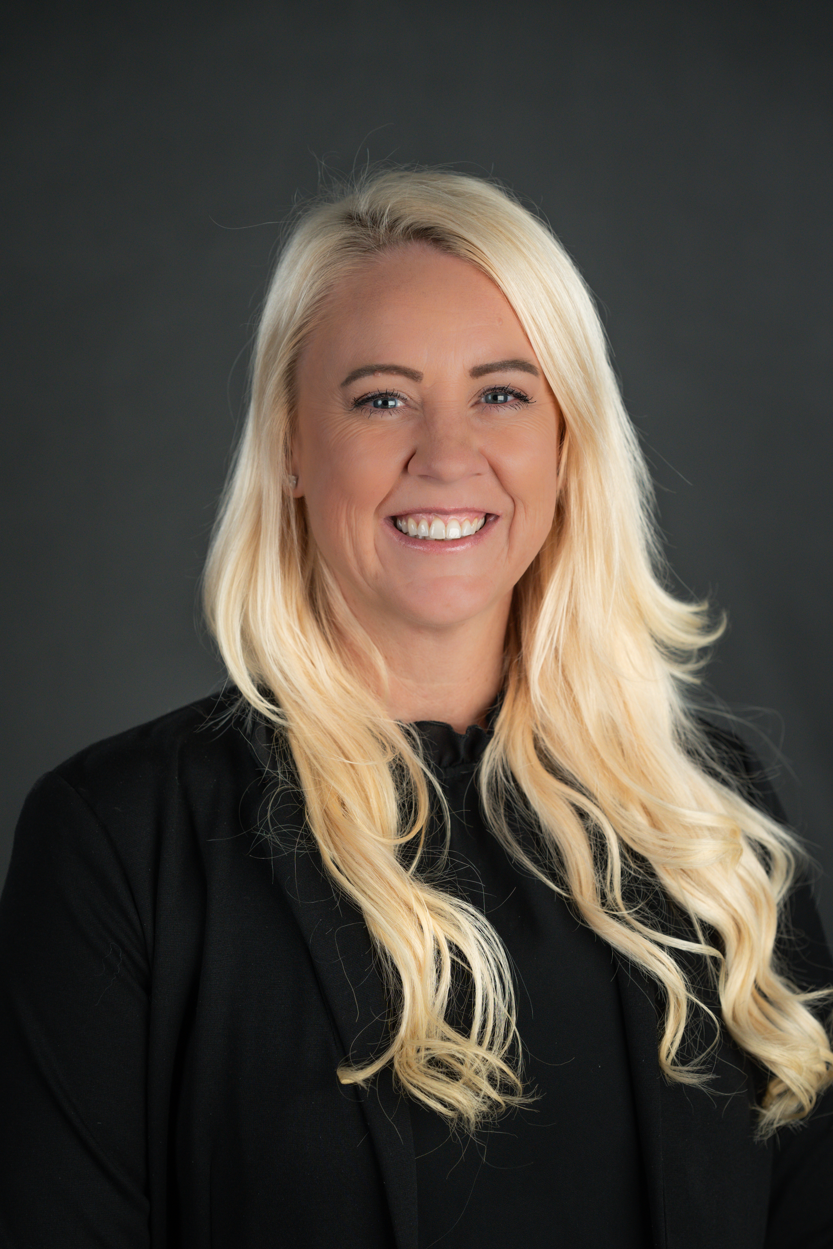 Head shot of Hailey Nanchy, woman wearing black suit with blond hair.